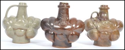 A group of three studio pottery vases of unusual form having shaped bodies with tapering necks, in