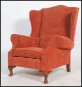 A 20th century good quality Chesterfield revival wing back armchair having scroll ends raised on
