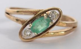 A hallmarked 9ct gold ring set with an oval cut emerald flanked by two bezel set diamonds in the Art