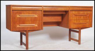 A 1970's retro Danish inspired teak wood writing table desk raised on shaped legs with a bank of