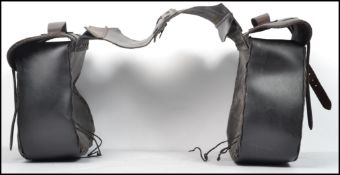 A set of vintage 20th century black leather bike parriers with straps having eagle insignia's. Bag