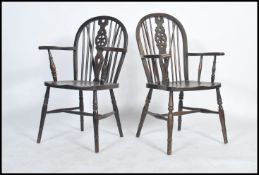 A pair of mid century beech and elm wood wheelback dining chairs being raised on turned legs