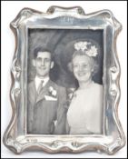 An early 20th century silver hallmarked wooden backed picture frame having scrolled edge work,
