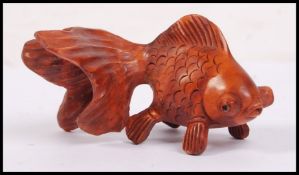 An oriental carved wooden netsuke in the form of a carp fish with large bulging eyes.