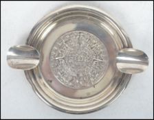 A silver ashtray of circular form, central Mayan design with two cigarette supports stamped to the