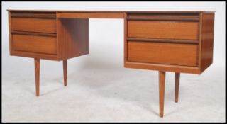 A 1970's retro teak wood Austinsuite writing table desk being raised on tapered legs with a series