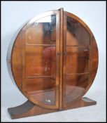 A 1930's Art Deco walnut circular china display cabinet raised on a shaped plinth having twin