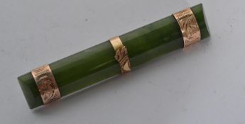 A 9ct gold and jade bar brooch having thee gold bands with pin to verso.