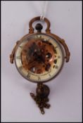 An unusual brass cased roman fish eye ball clock with bell to bottom and swing handle, the dial