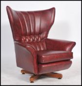 A good 1960's Parker Knoll type retro  batwing swivel armchair being raised on a teak quadruped base