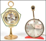 A vintage retro 20th century Metamec clock raised on a red plastic stand along with another clock by