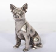 A silver plated bronze figurine of a dog modelled in a seated position.