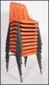 A set of 1970's orange and tubular metal stacking chairs having orange plastic seat with pierced