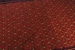 A Persian Islamic hand woven Bokhara rug having a red ground decorated in geometric patterns with