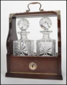 A mahogany and silver white metal mounted twin bottle Tantalus having fold out front with swing