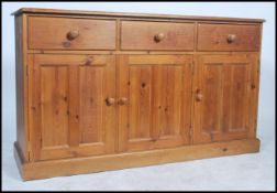A 20th century pine kitchen dresser base with rounded edge to top, fitted three frieze drawers,
