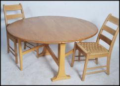 A retro 1970's elm and beech Ercol drop leaf gate leg dining table with applied label together