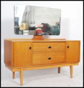 A 1970's retro teak wood dressing table raised on tapered legs with a series of cupboard and drawers