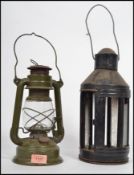 Two vintage 20th industrial century storm lights having metal cages with glass panels and swing