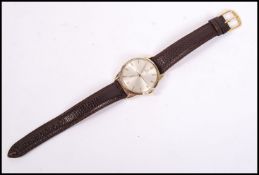 A vintage Omega gents wrist watch mounted an a brown leather strap, the silvered dial having baton