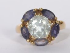 A 9ct gold dress ring set with a central pale blue stone surrounded by oval cut purple stones.