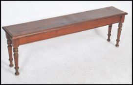 An early 20th century solid oak pig refectory bench having a planked top raised on turned legs.
