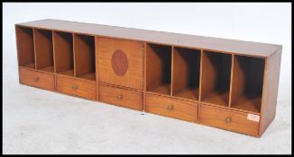 A 20th century long pigeon hole desk tidy of elongated form having central cupboard with eight holes