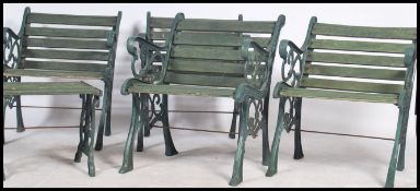 A group of four 20th century heavy cast metal garden chairs with slat seats and back rests, scroll