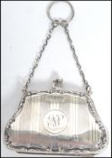 An Edwardian silver hallmarked ladies purse having a scrolled border with carry chain to top.