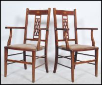 A pair of Edwardian mahogany inlaid salon armchairs. Raised on turned legs united by peripheral