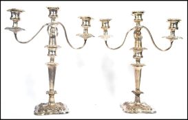 A pair of three sconce silver plated candelabras having scrolled arms with rococo influence sconces,