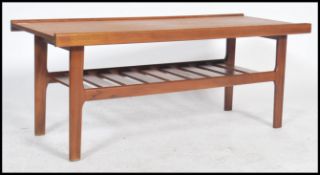 A vintage mid century teak wood coffee table with a banded edge rail and magazine rack to the