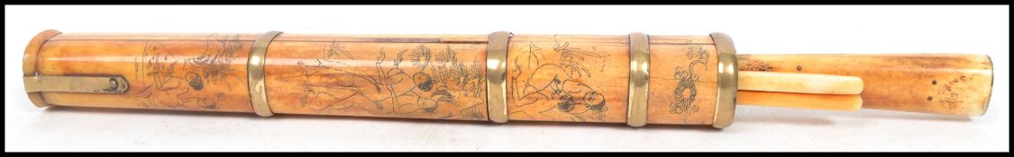 A vintage Oriental bone trousse consisting of chopsticks and holder with knife having scenes of