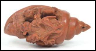 An Oriental miniature carved wooden netsuke in the form of a cornucopia nautical shell depicting two