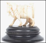 A 19th century ivory carved figurine group of a robed Arabic man stood next to horse with head down,