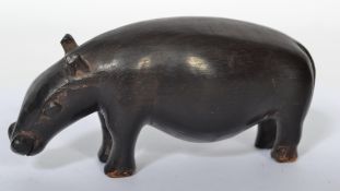 An African tribal carving of a pygmy hippopotamus of ebonised wooden construction.