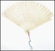 A 19th century Indian bone ladies fan having twenty repetitive carved fret pierced panel blade