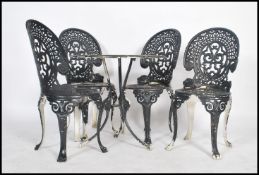 A vintage retro 20th century cast aluminium garden table and four chairs having a pierced