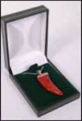 A silver and apple coral pendant in the form of a tooth mounted on a sterling silver necklace