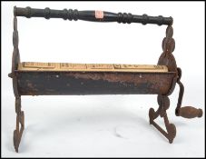 A vintage cast iron newspaper log roller, cast from iron with a central mangle connected to a rotary