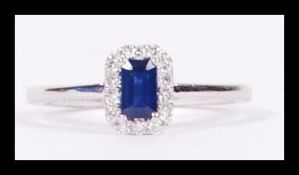 An 18ct white gold diamond and sapphire ring having a central faceted sapphire surrounded by a