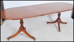 A good quality mahogany ebony inlaid Regency revival twin pedestal dining table being raised on