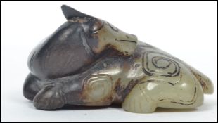An unusual Chinese mottled green and brown jade carved study of a recumbent ox having a chased