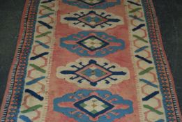 A 20th century carpet / rug runner salmon ground decorated throughout with geometric patterns.