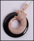 A sterling silver gilt onyx pendant in the form of a leopard having an emerald eye with sterling