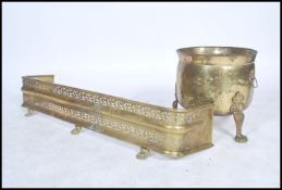 A late 19th century brass fire fender together with a lidded Art's and Craft's coal scuttle.