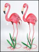 A pair of decorative painted metal garden statue ornaments in the form of flamingo's