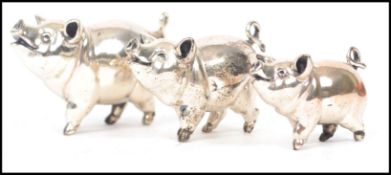 A graduating set of 3 silver 925 pigs, all with curly tails and raised ears being stamped to the