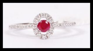 An 18ct white gold ruby and diamond cluster ring, having a central ruby adorned with a halo of