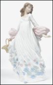 A Lladro ceramic figurine entitled ' Spring Splender ' of a lady holding a floral basket in